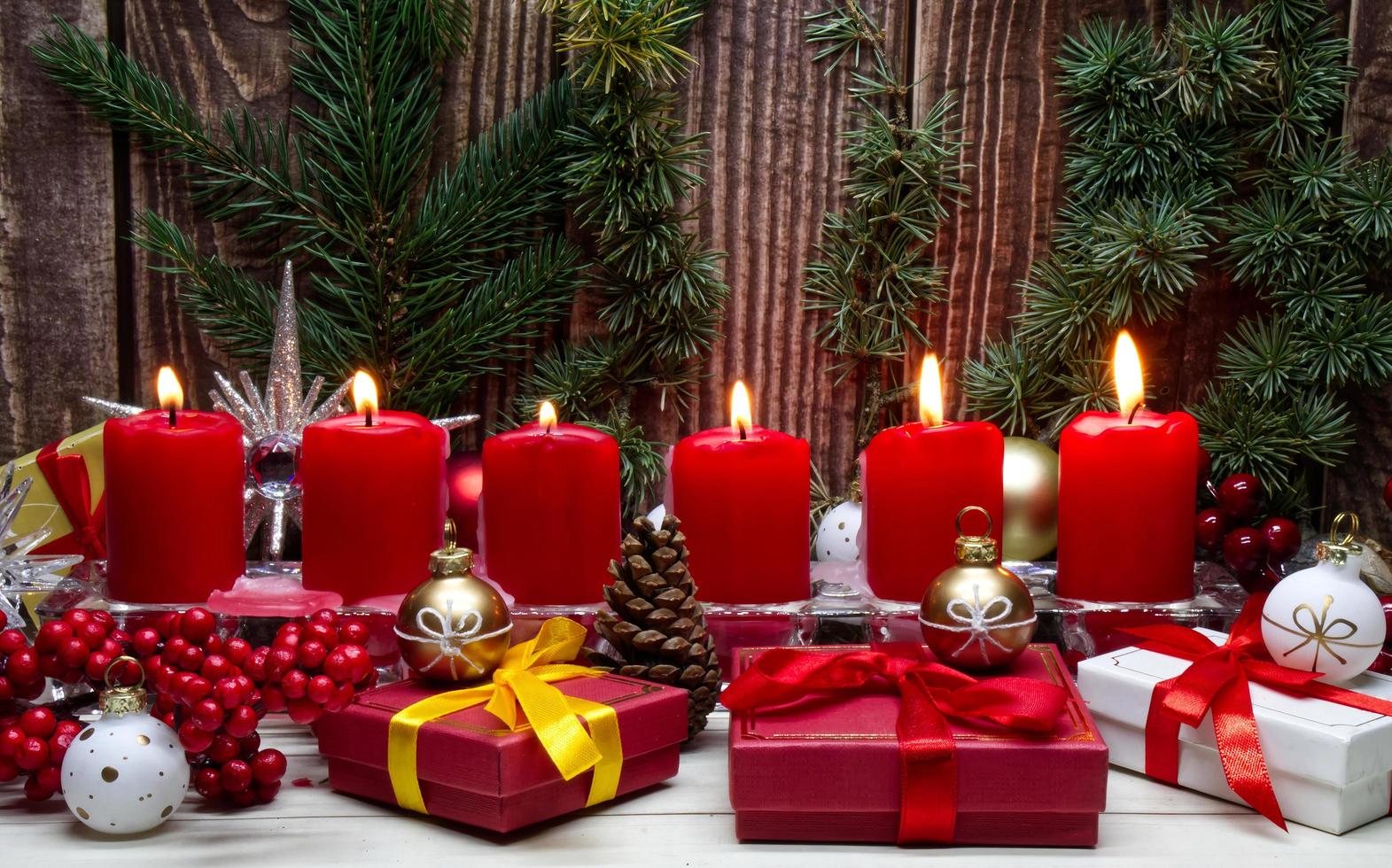 rood Kerstmis kaarsen en Kerstmis geschenk dozen tegen houten achtergrond foto