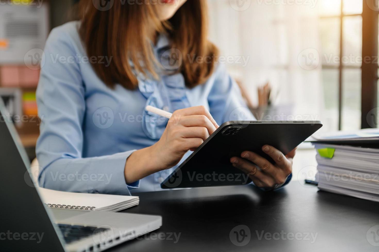 zelfverzekerde zakenvrouw die op laptop en tablet werkt op haar werkplek op modern kantoor. foto