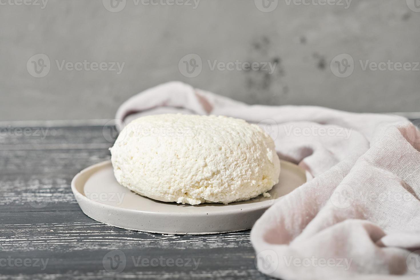 eigengemaakt zacht wit kaas Aan houten zwart achtergrond, huis huisje kaas maken. geit melk kaas Aan grijs cement bord. foto