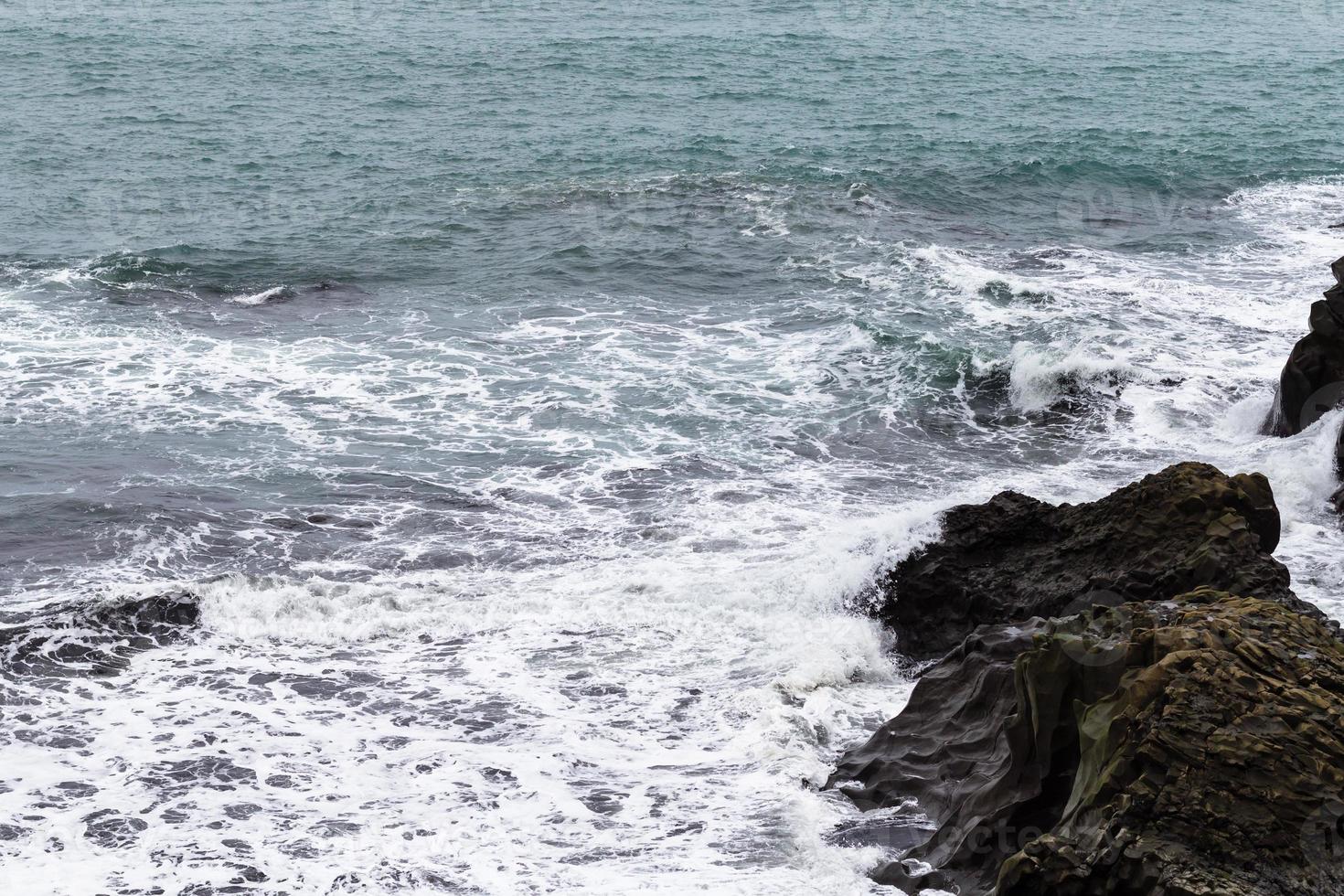 surfen en rotsen in atlantic oceaan in IJsland foto