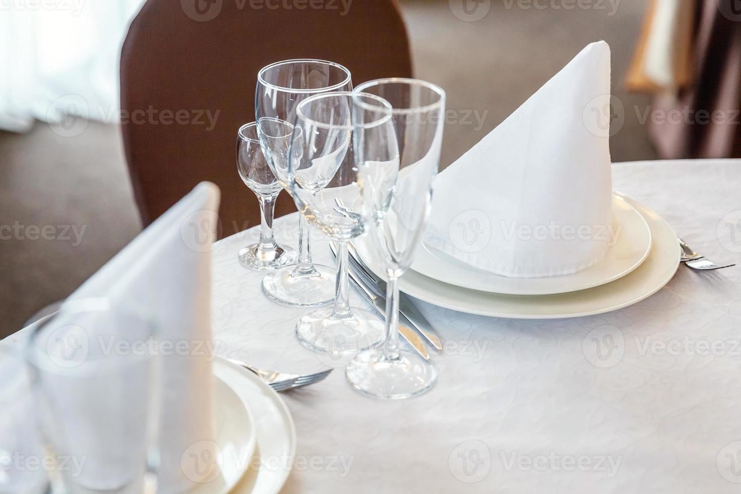 fancy tafel set voor het diner met servetglazen in restaurant, luxe interieur achtergrond. bruiloft elegante banket decoratie en items voor eten geregeld door cateringservice op witte tafelkleed tafel. foto