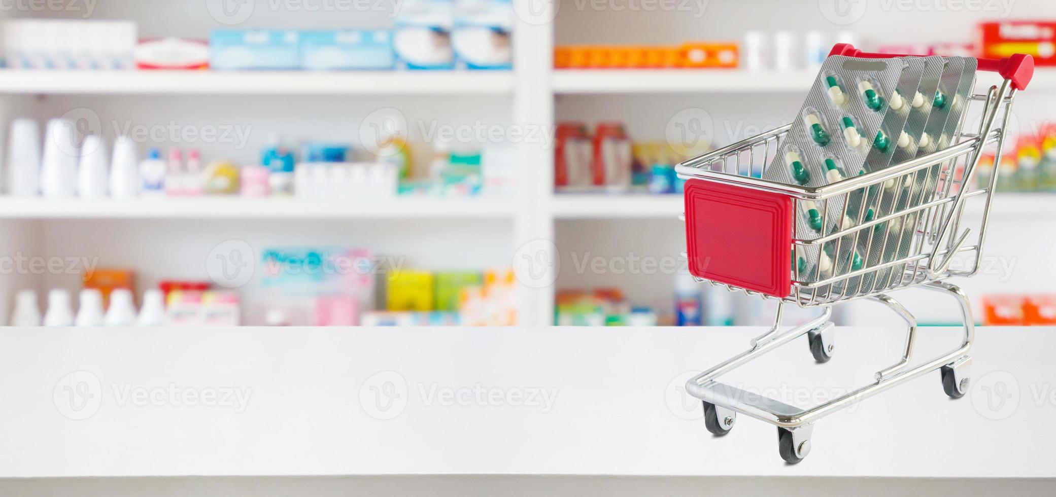 geneeskunde pillen capsule in winkelwagen op apotheek winkel teller met onscherpte drogisterij planken intreepupil achtergrond foto