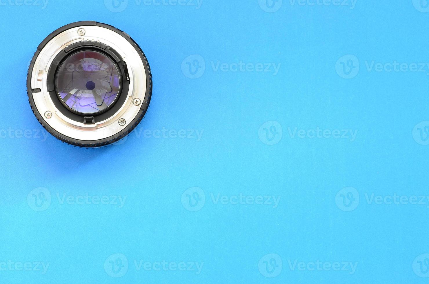 een fotografisch Lens liggen Aan een helder blauw achtergrond. ruimte voor tekst foto
