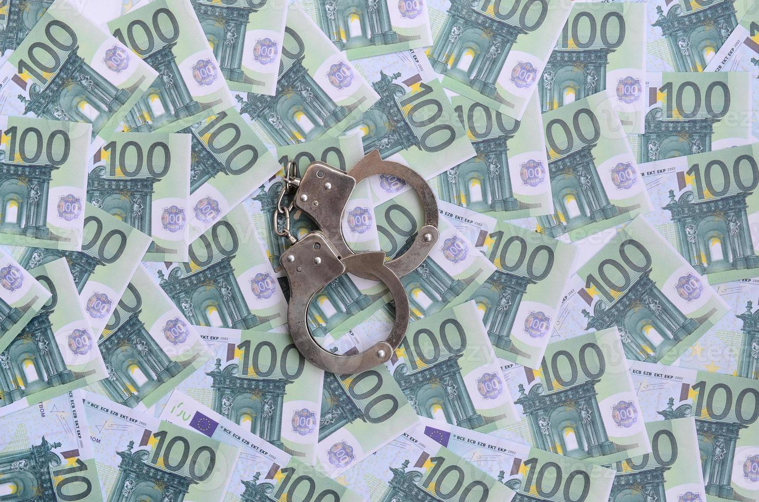 Politie handboeien leugens Aan een reeks van groen monetair denominaties van 100 euro. een veel van geld vormen een eindeloos hoop foto