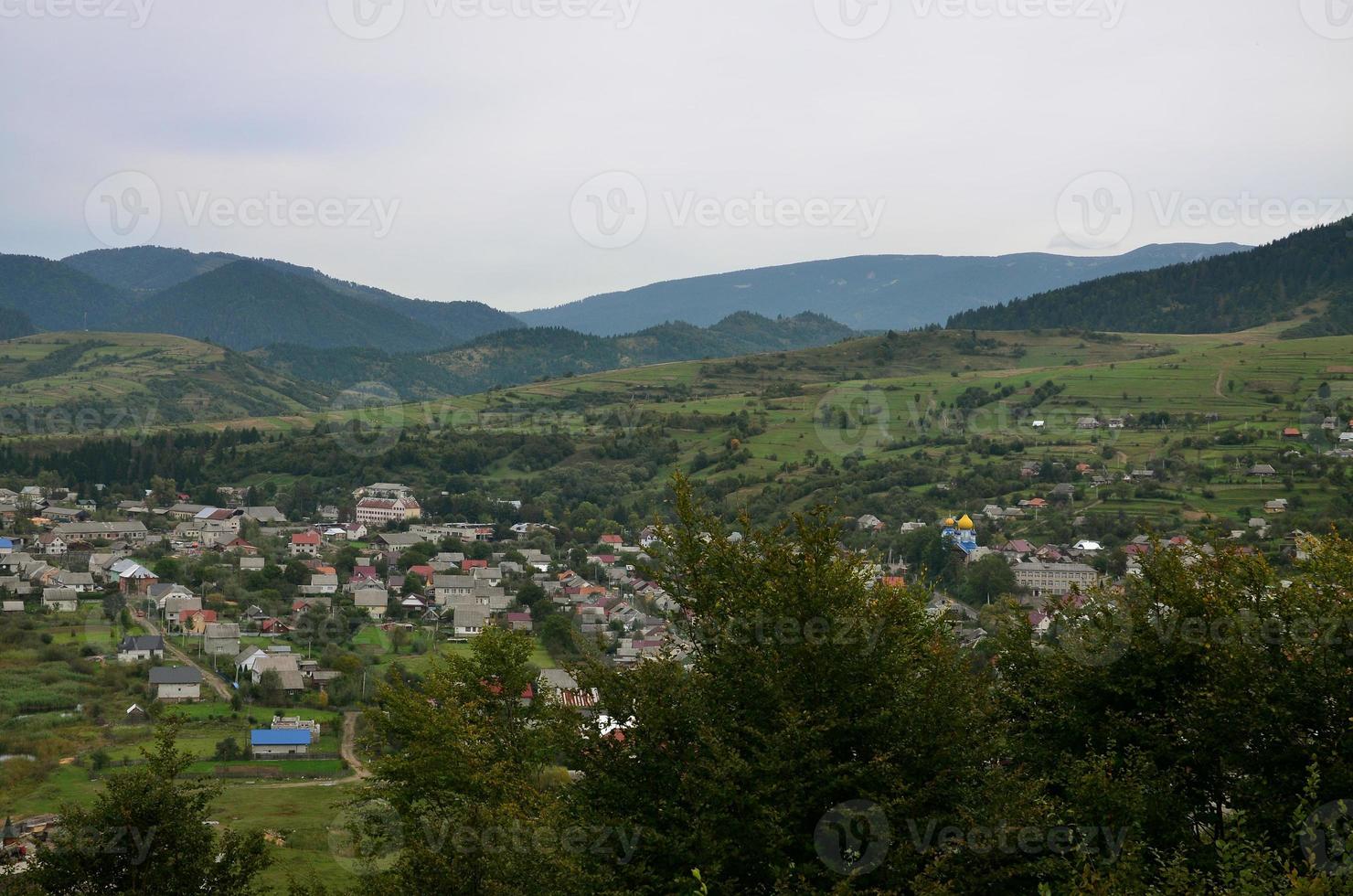 een mooi visie van de dorp van mezhgorye, Karpaten regio. een veel van woon- gebouwen omringd door hoog Woud bergen en lang rivier- foto