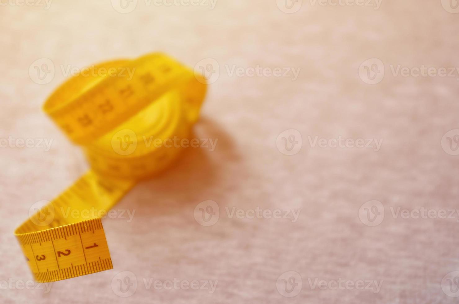 geel meten plakband leugens Aan een grijs gebreid kleding stof foto