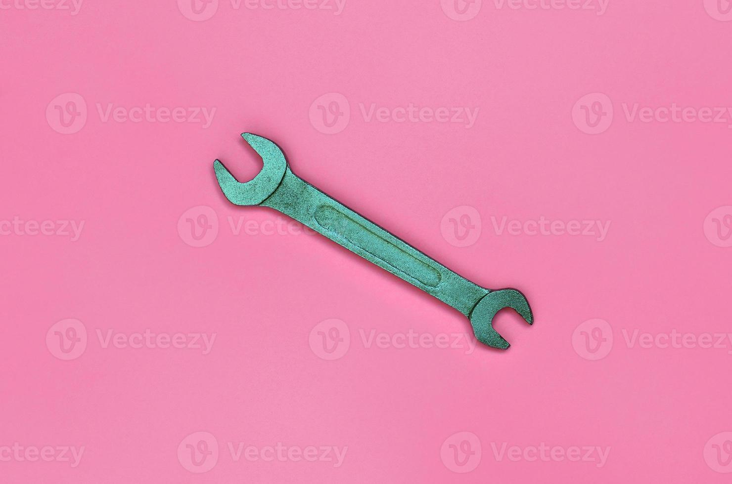 metalen moersleutel liggen Aan structuur achtergrond van mode pastel roze kleur papier in minimaal concept foto