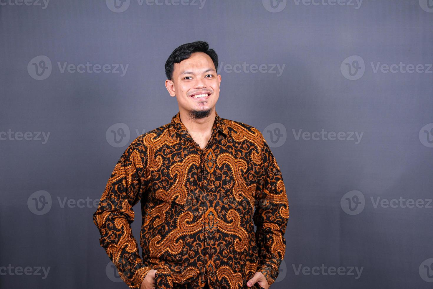portret van jong Aziatisch vent in een batik poseren geïsoleerd Aan grijs achtergrond foto