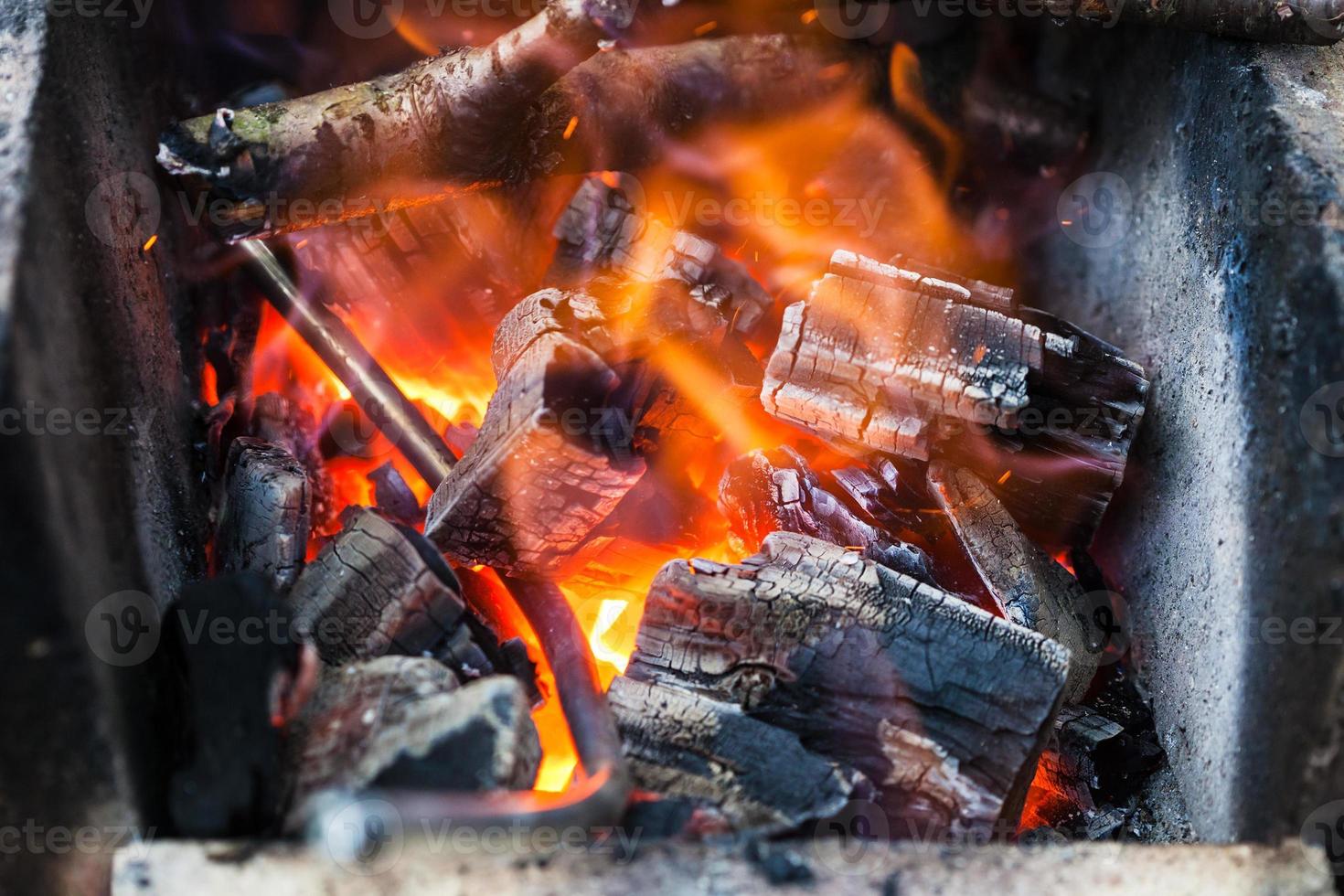 ijzer hengel is verwarmde in brandend houten kolen foto