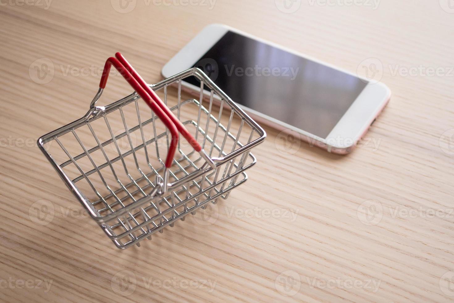 mobiel telefoon met mand Aan hout tafel achtergrond boodschappen doen online concept foto