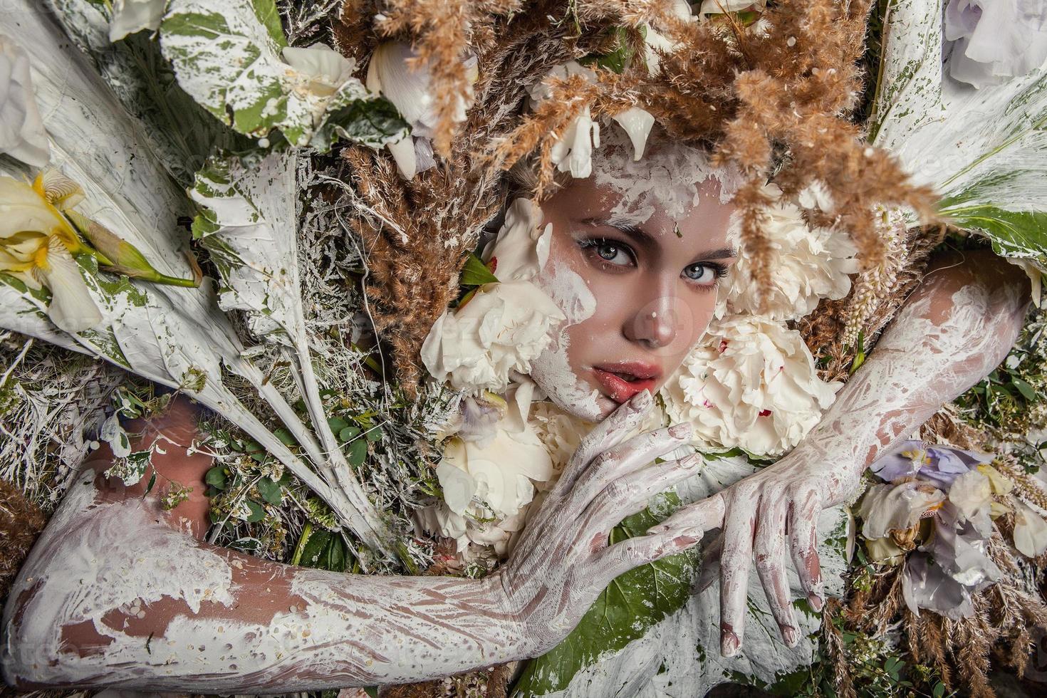 sprookjesmeisje portret omgeven met natuurlijke planten en bloemen. foto