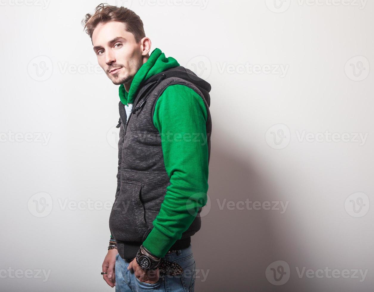 aantrekkelijke jonge man in grijs vest en groene trui. foto