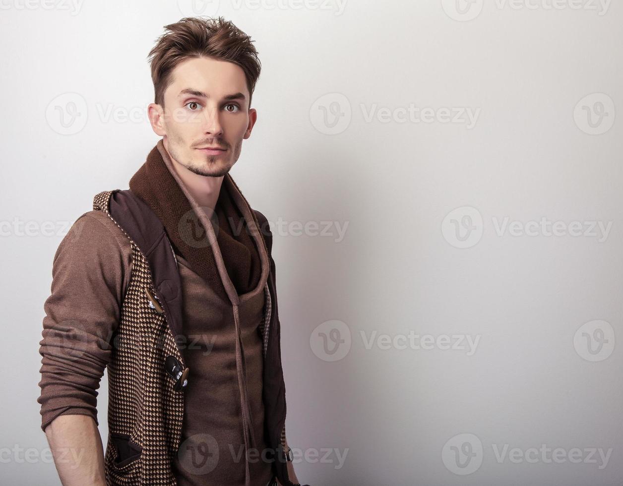 aantrekkelijke jonge man in een bruine trui poseren in studio. foto