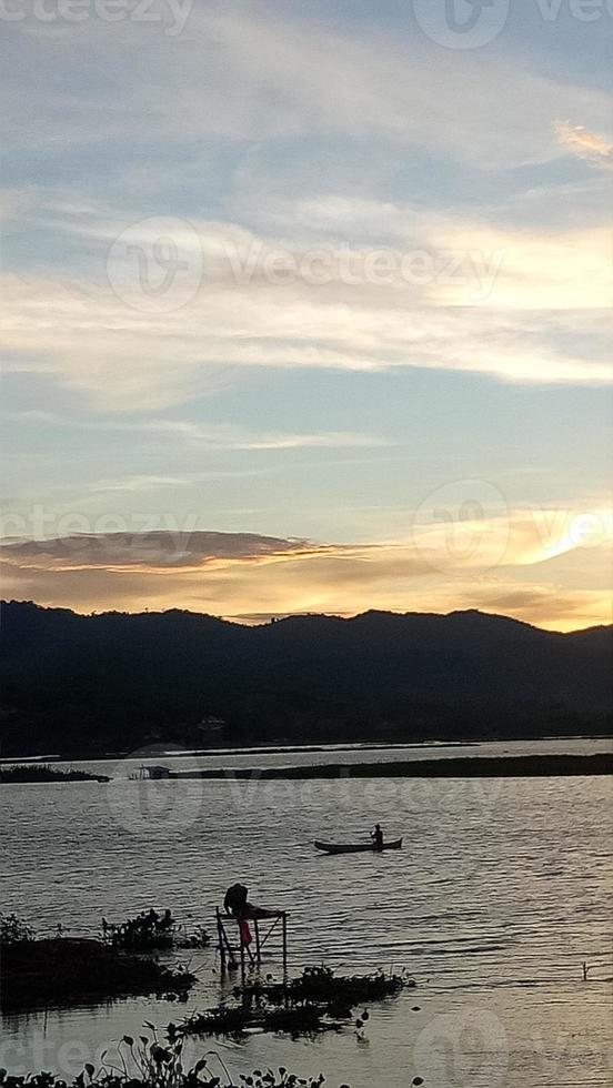 silhouet van een Mens visvangst in de middag. zonsondergang Aan meer limbo, Indonesië foto