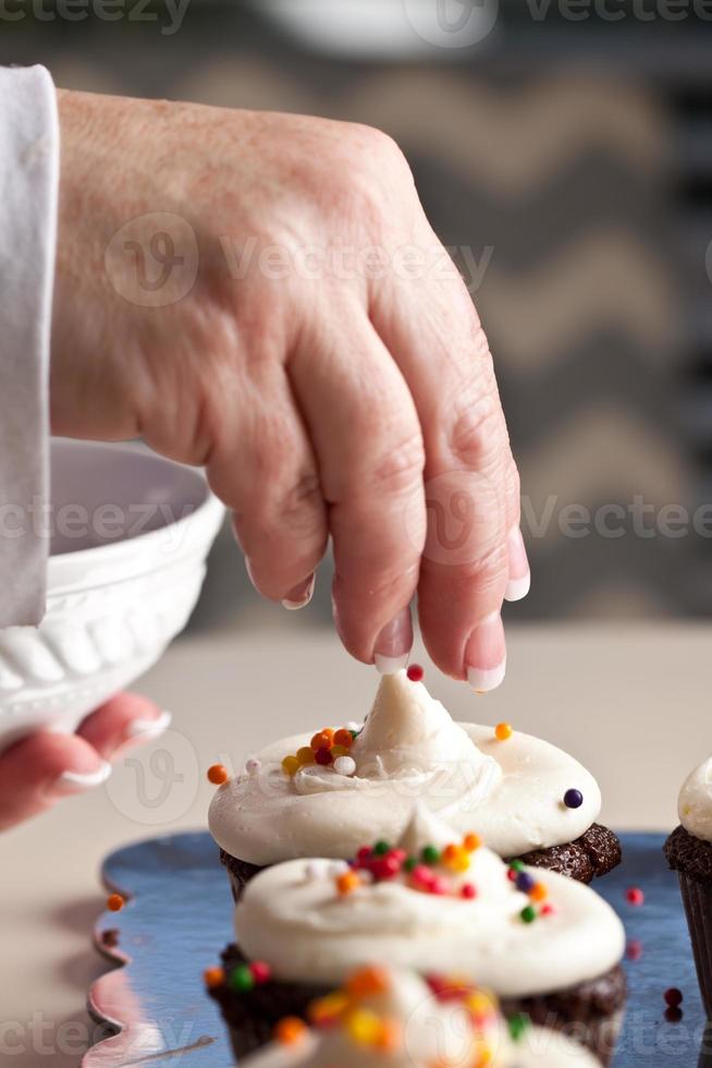 chef's hand hagelslag zetten cupcakes foto