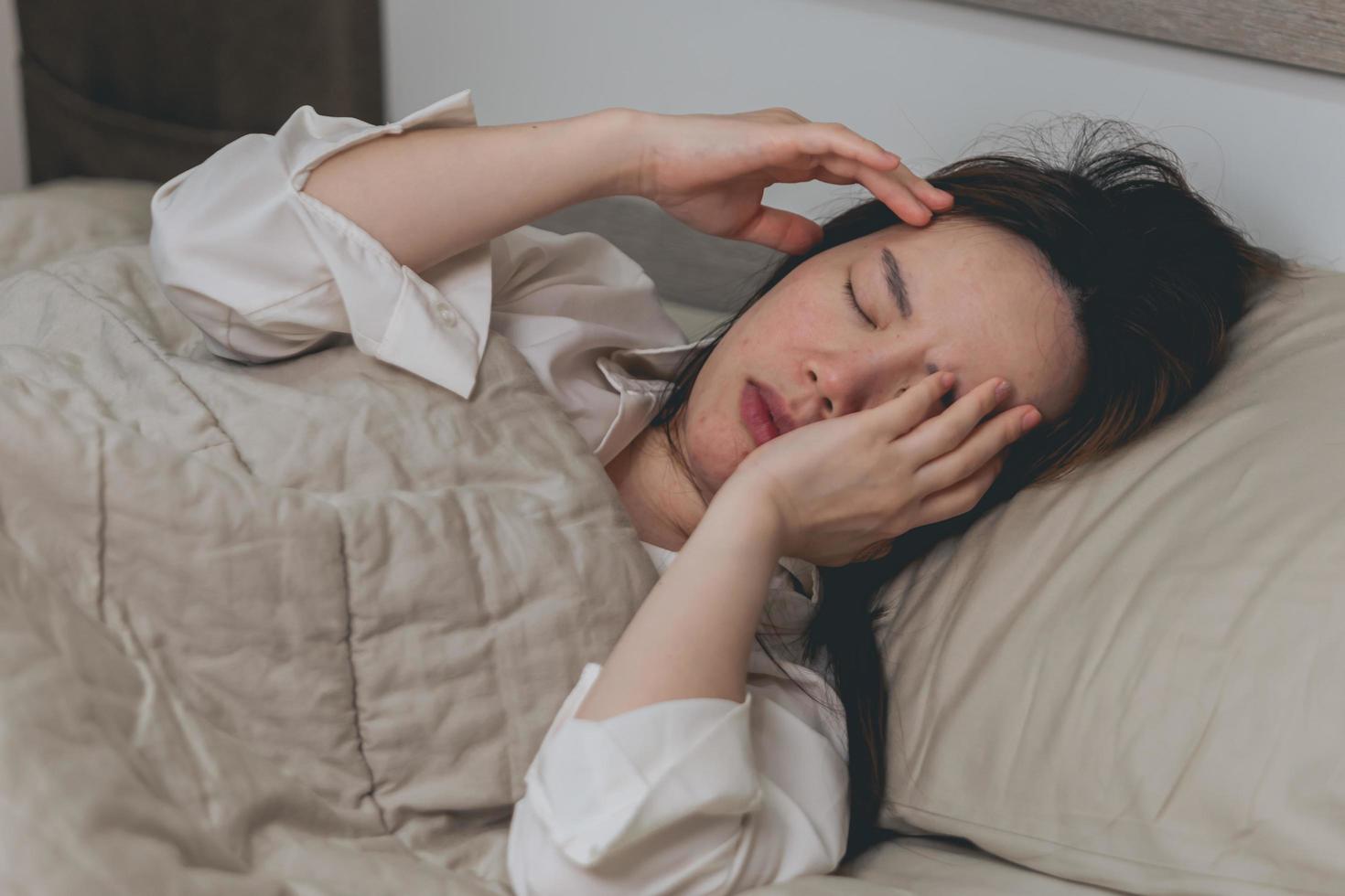 schoonheid, jong vrouw met hoofdpijn Aan bed.ziek vrouw Aan bed concept van maagpijn, hoofdpijn foto