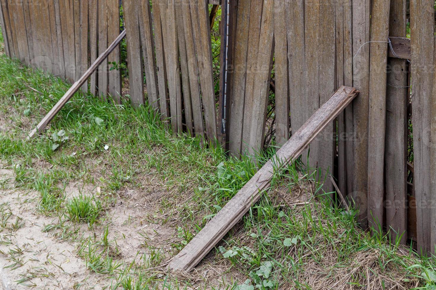 oud stoffig gammel houten hek met plank rekwisieten en gras dichtbij omhoog met selectief focus foto