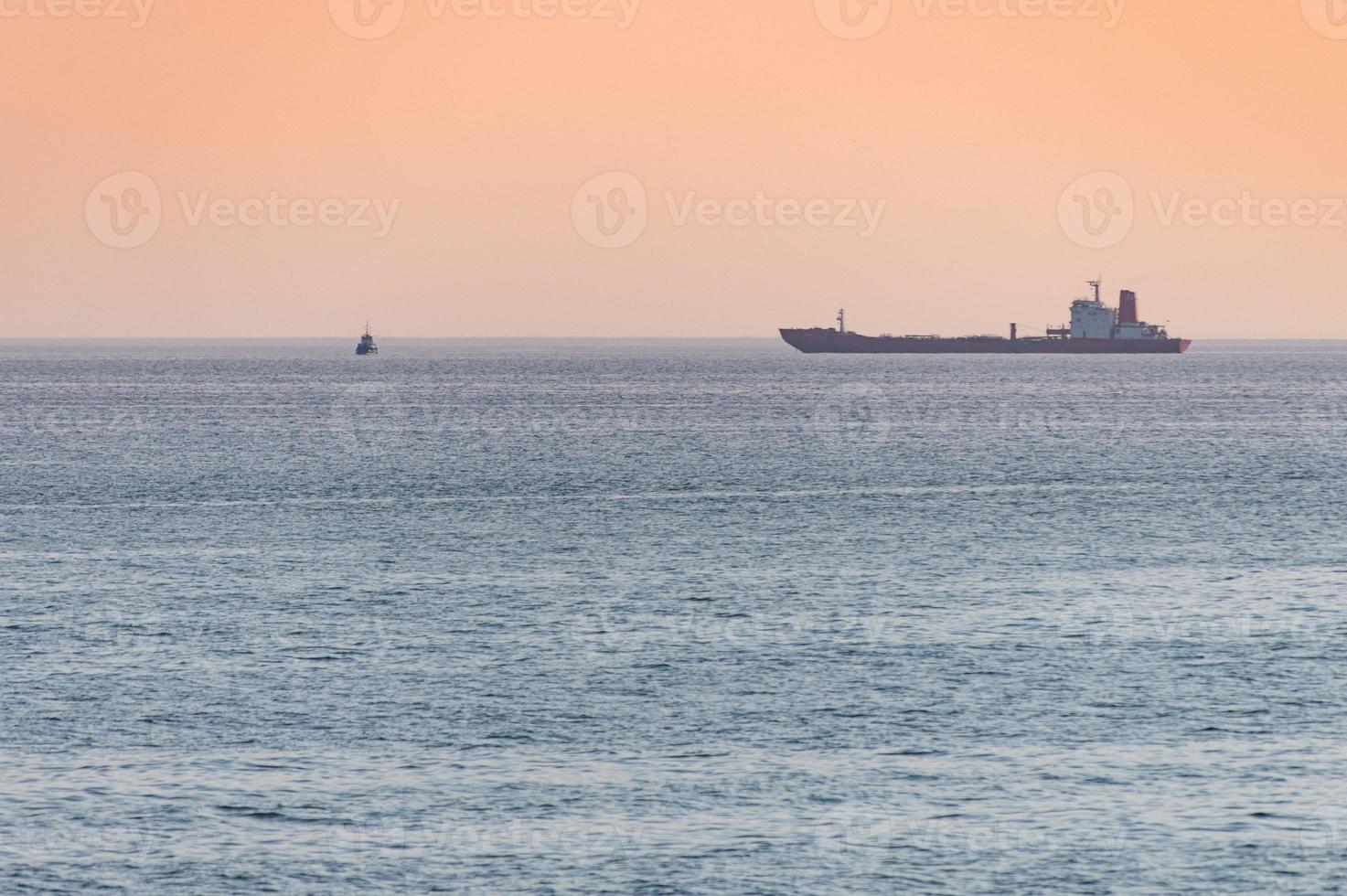 kleine sleepboot en groot vrachtschip. prachtige zonsondergang over zee. adembenemende reisweergave, kopieer ruimte. foto