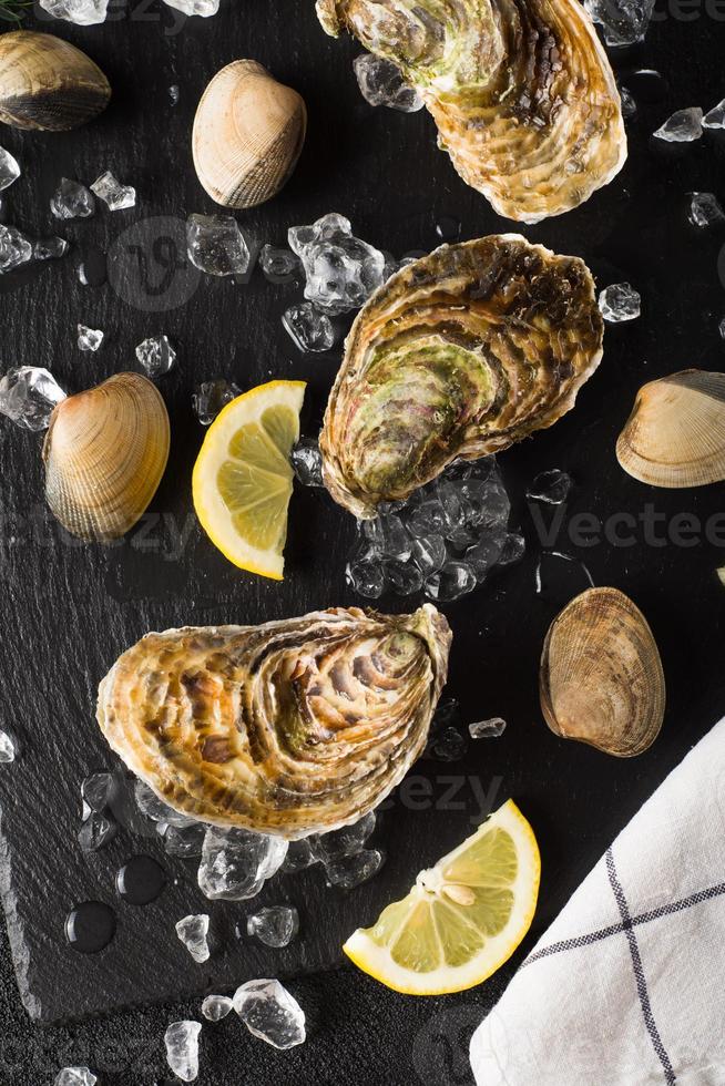 verse oesters en mosselen op een zwarte stenen plaat foto