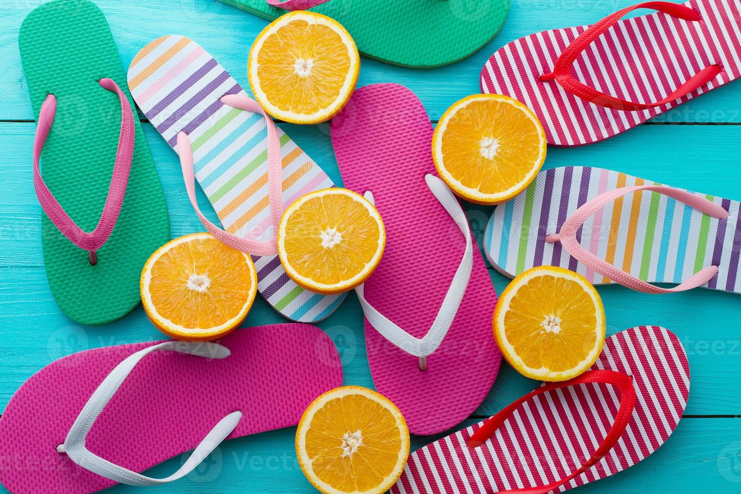 zomer pret tijd, omdraaien flopt. slippers en oranje fruit Aan blauw houten achtergrond. bespotten omhoog. top visie. sandalen foto