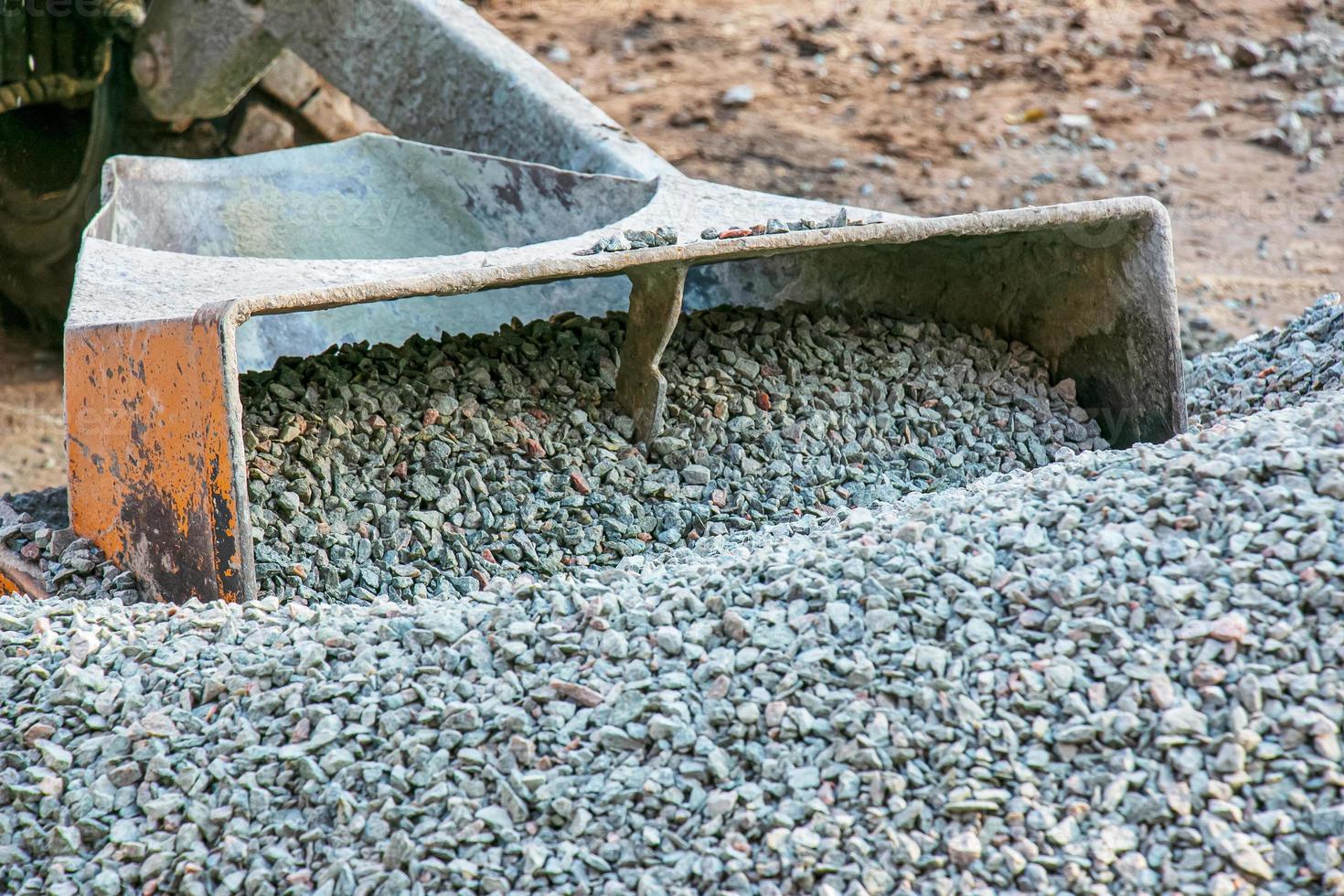 mobiel beton menger Bij de bouw plaats. detailopname van grind wezen geladen in een beton maken machine foto