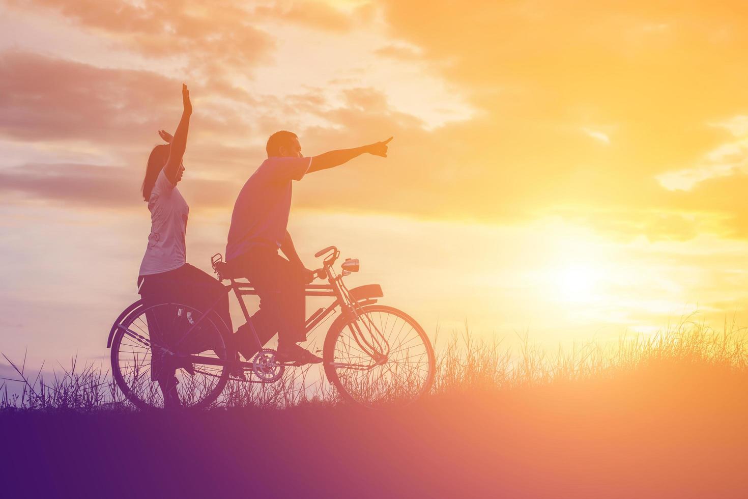 silhouet van zoet jong paar in liefde gelukkig tijd Aan fiets foto