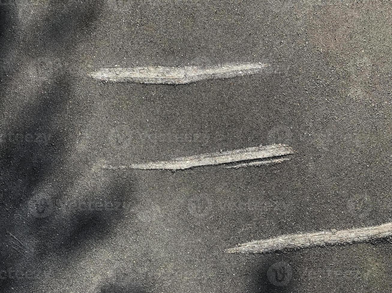donker asfalt structuur met drie oud gekrast strepen, abstract achtergrond. foto