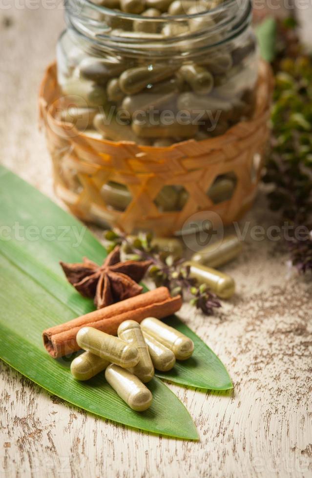 kruid capsule met groene kruiden blad op hout foto