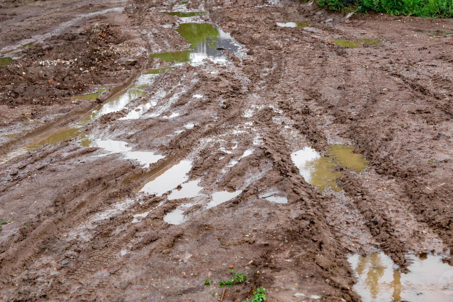 vuil klei modder tweesprong met plassen en band sporen - detailopname met selectief focus en lineair perspectief foto