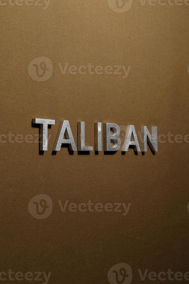 de woord taliban gelegd met zilver metaal brieven Aan ruw bruinen khaki canvas kleding stof foto