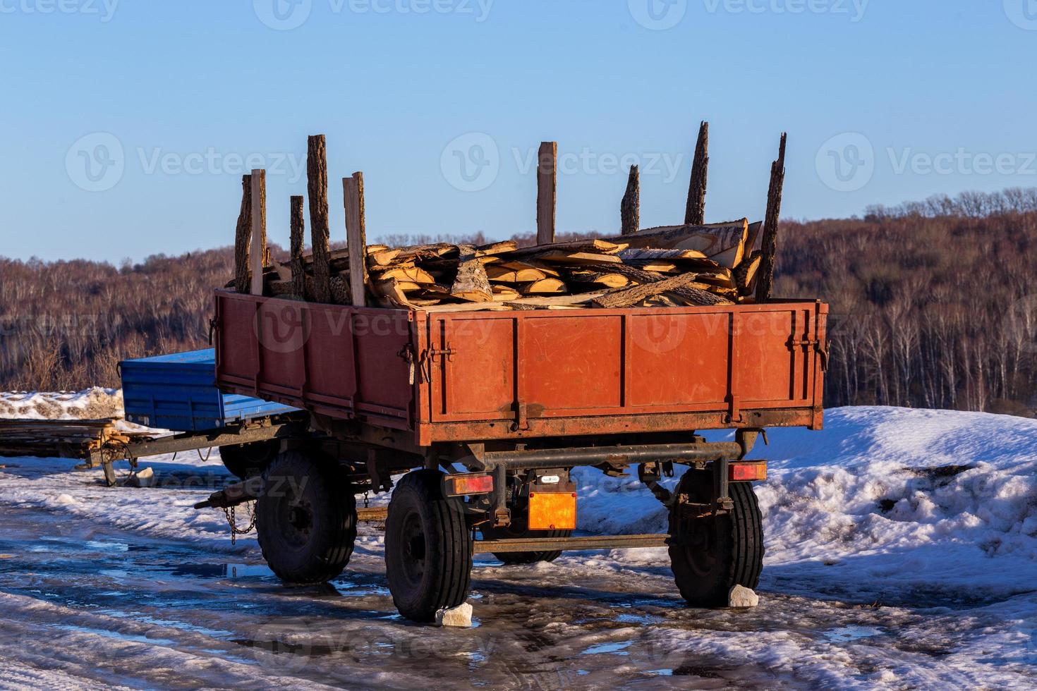 oud rustiek aanhangwagen met brandhout timmerhout restjes Bij winter daglicht foto