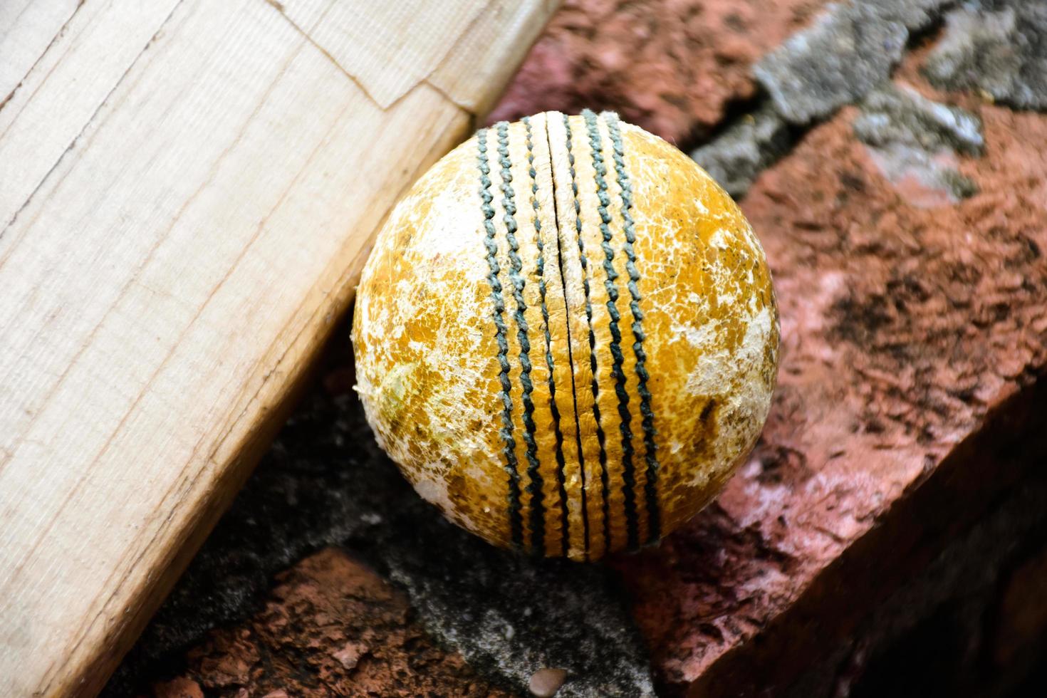 krekel sport uitrustingen Aan steen, knuppel, wicket, oud leer bal, zacht en selectief focus. foto