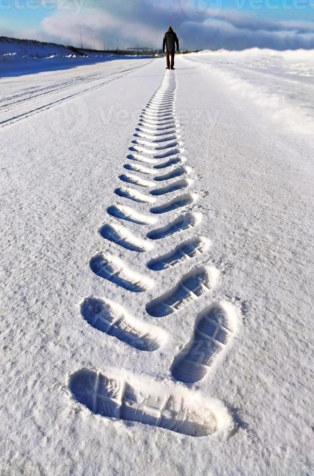 Mens van achter maken een spoor in de sneeuw, schoen prints in de sneeuw foto