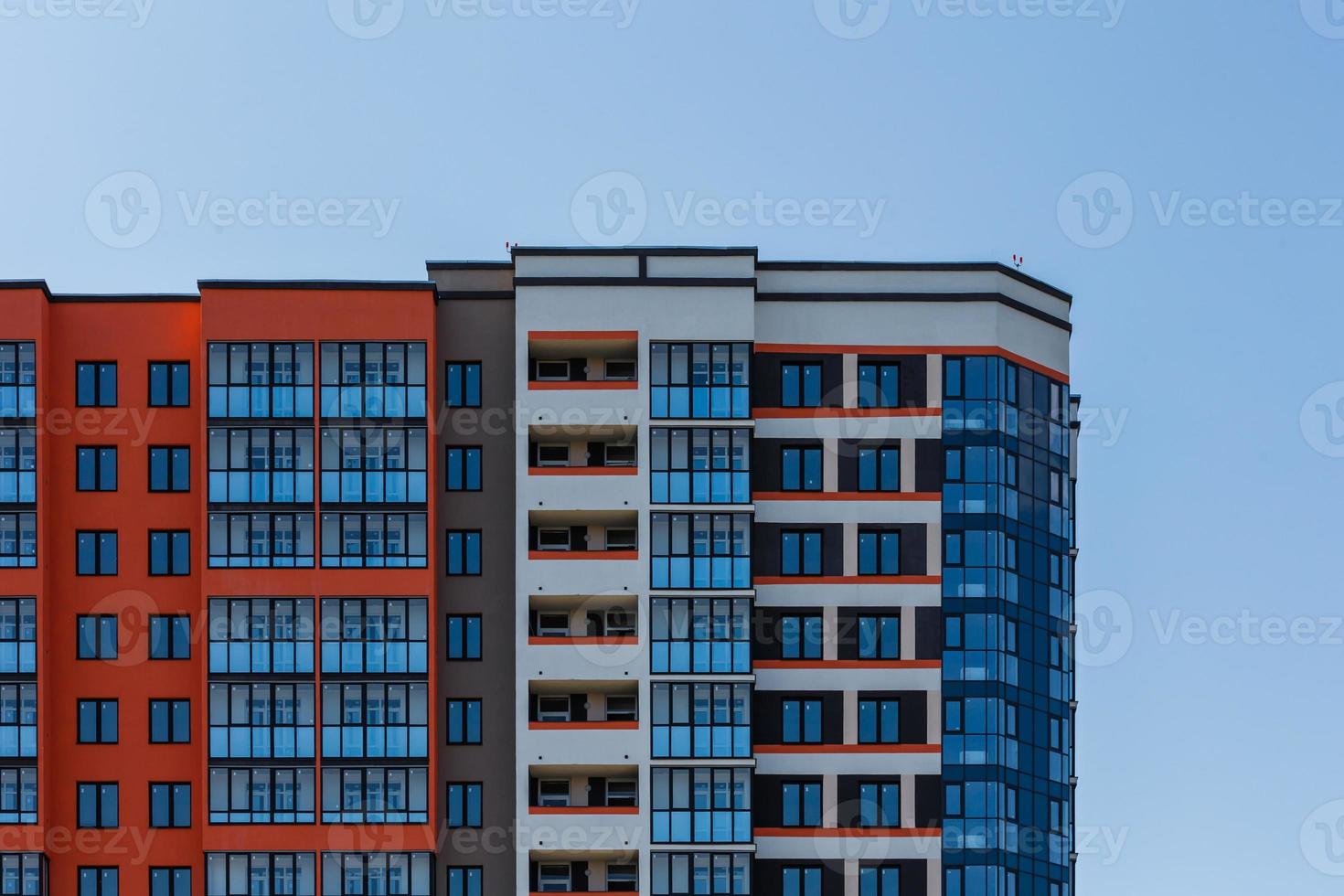 nieuw hoog stijgen appartement gebouw met meerdere balkon en ramen Aan blauw lucht met wit wolken achtergrond foto