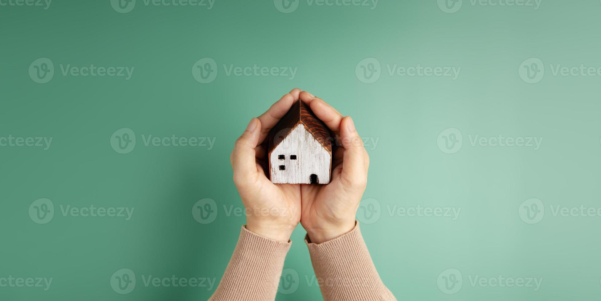 huis en familie verzekering concepten. hand- Holding een houten speelgoed- huis met liefde en teder zorg. klant zorg. top visie met meer kopiëren ruimte foto