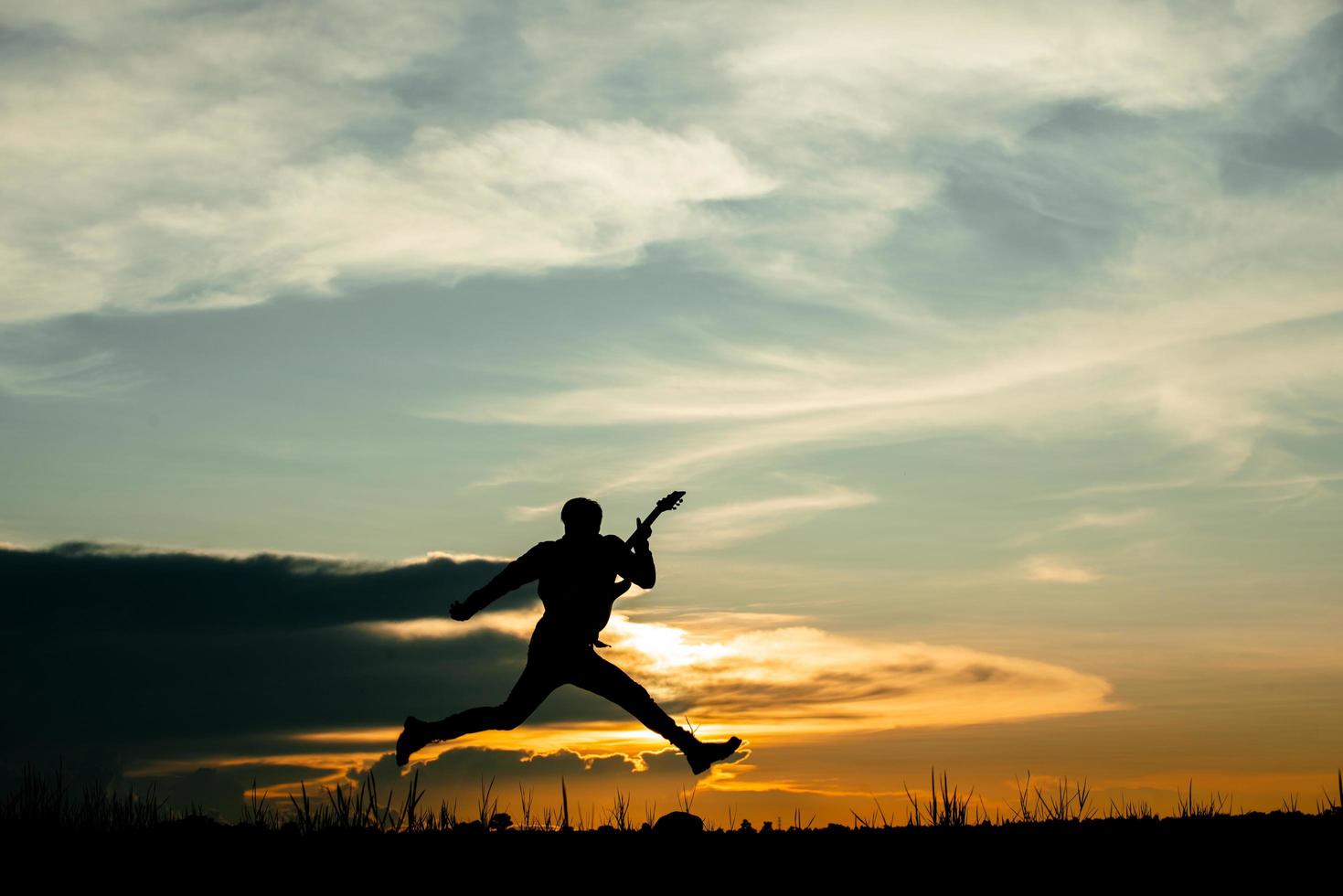 man gitaarspelen met zonsondergang achtergrond foto