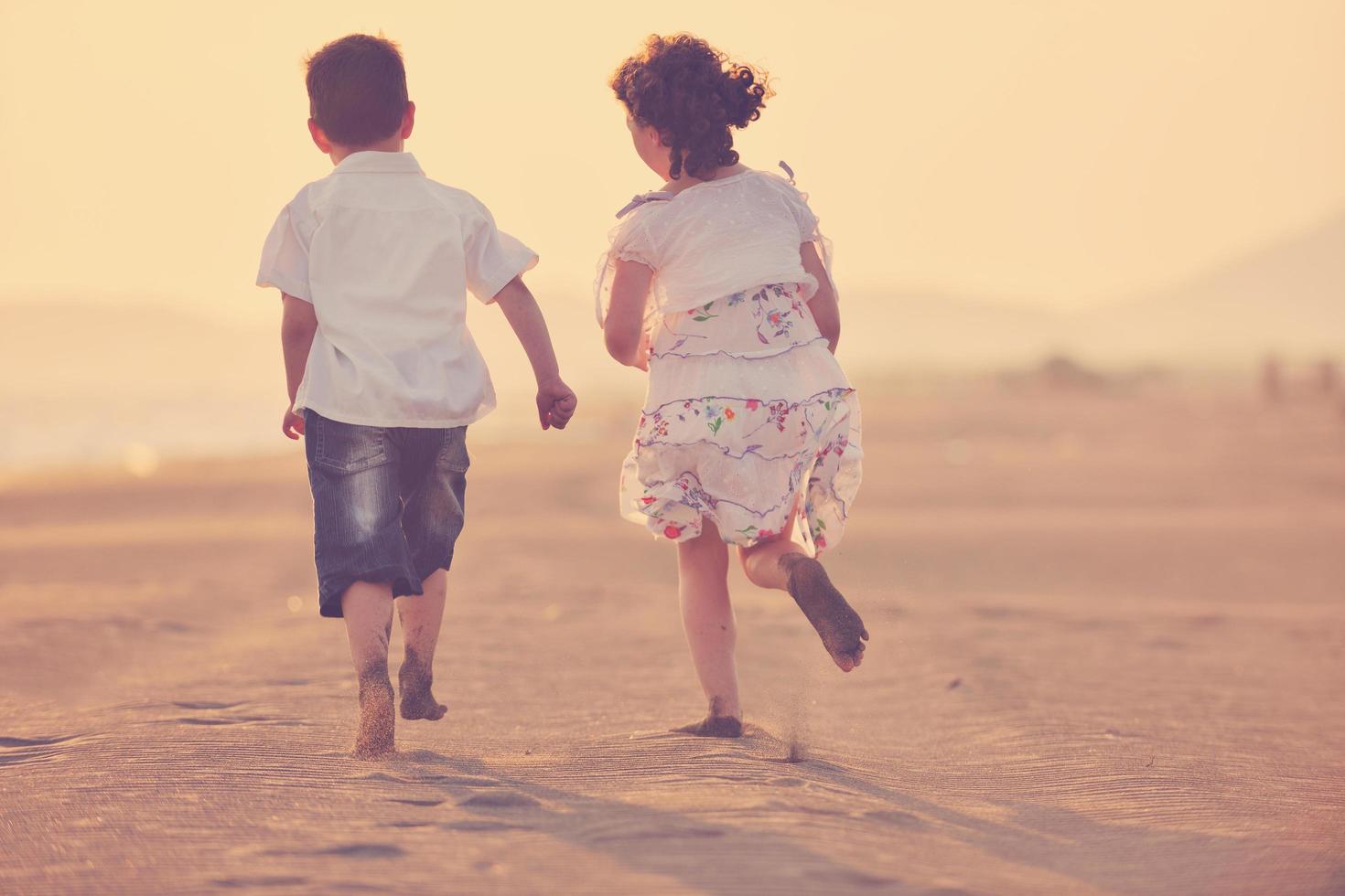 gelukkig jong familie hebben pret Aan strand Bij zonsondergang foto