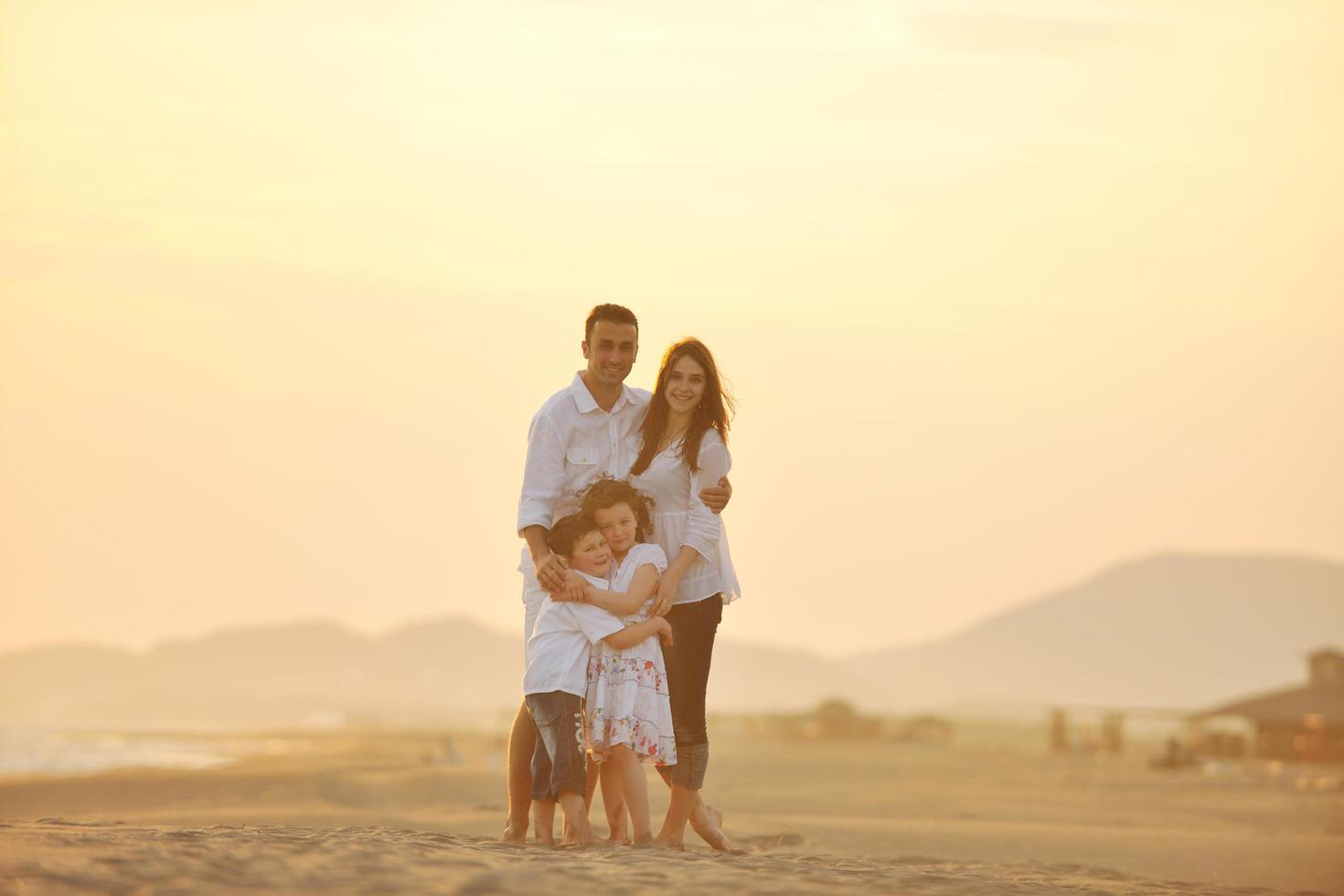 gelukkig jong familie hebben pret Aan strand Bij zonsondergang foto