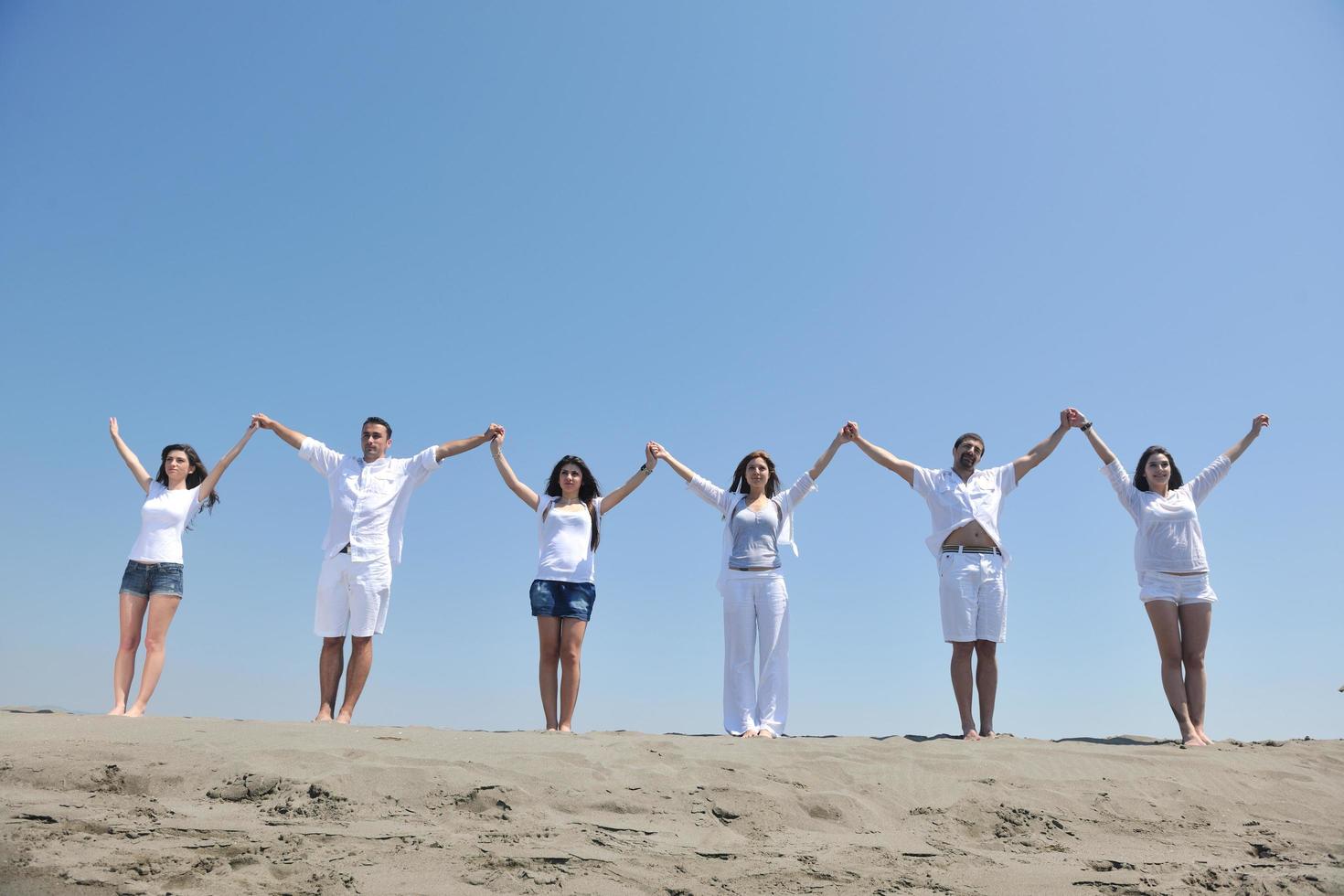 gelukkig mensen groep hebben pret en rennen Aan strand foto