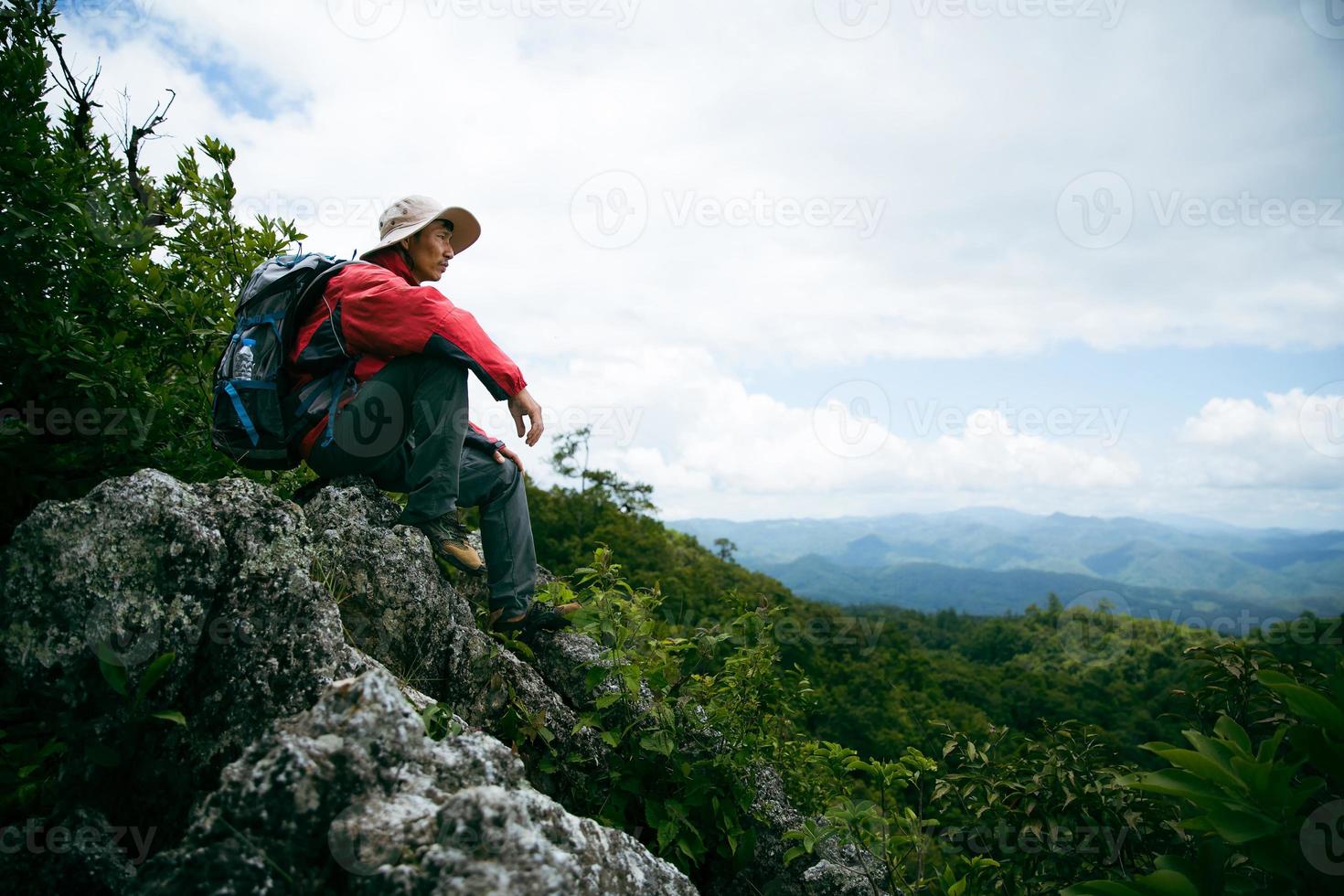 jonge persoon wandelen man op de bovenste rots, rugzak man kijken naar prachtige bergvallei bij zonlicht in de zomer, landschap met sport man, hoge heuvels, bos, lucht. reizen en toerisme. foto