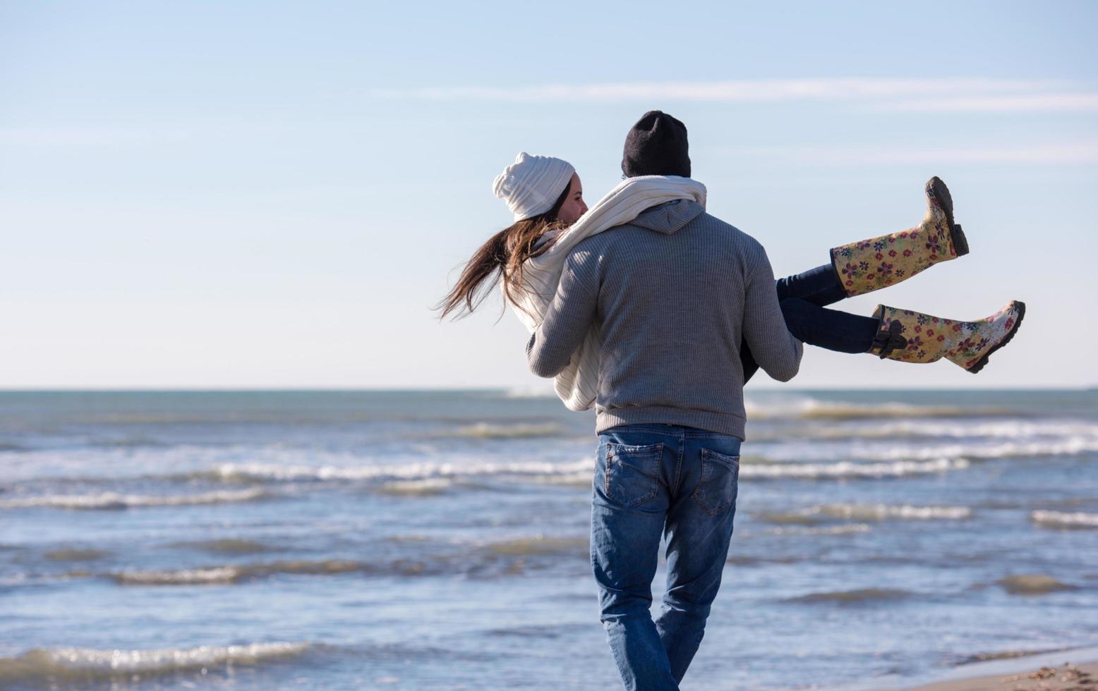 liefhebbend jong paar Aan een strand Bij herfst zonnig dag foto