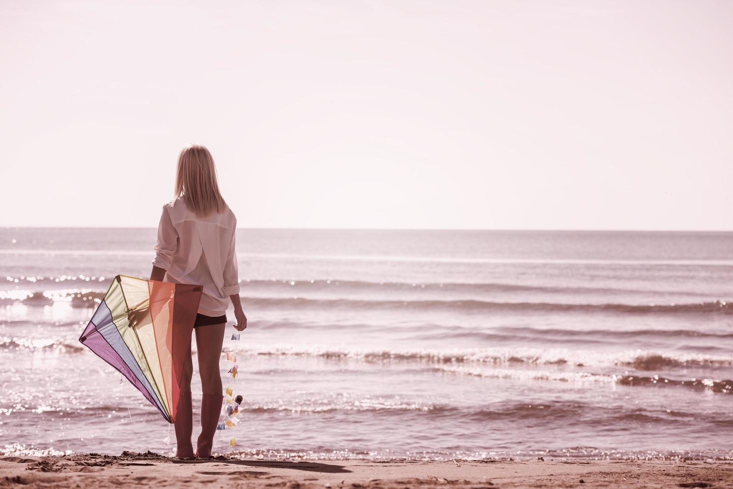 jong vrouw met vlieger Bij strand Aan herfst dag foto