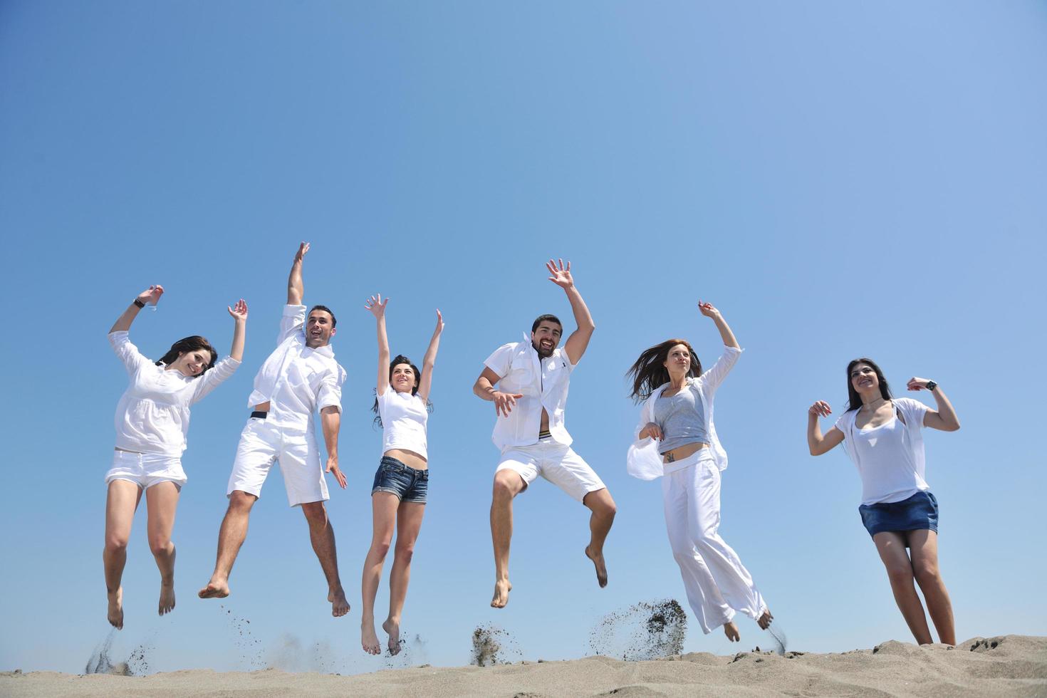 gelukkig mensen groep hebben pret en rennen Aan strand foto