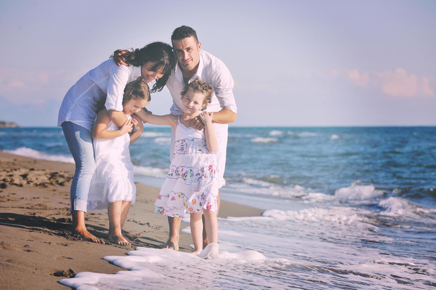 gelukkig jong familie hebben pret Aan strand foto