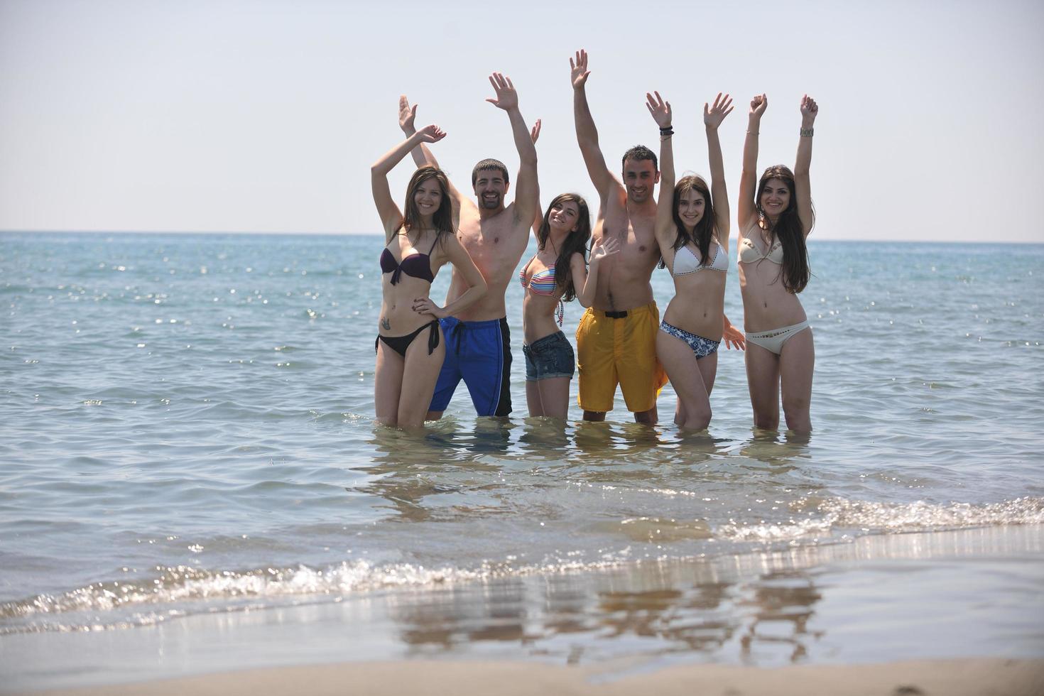 gelukkig mensen groep hebben pret en rennen Aan strand foto