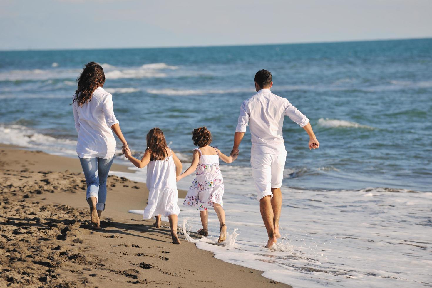 gelukkig jong familie hebben pret Aan strand foto