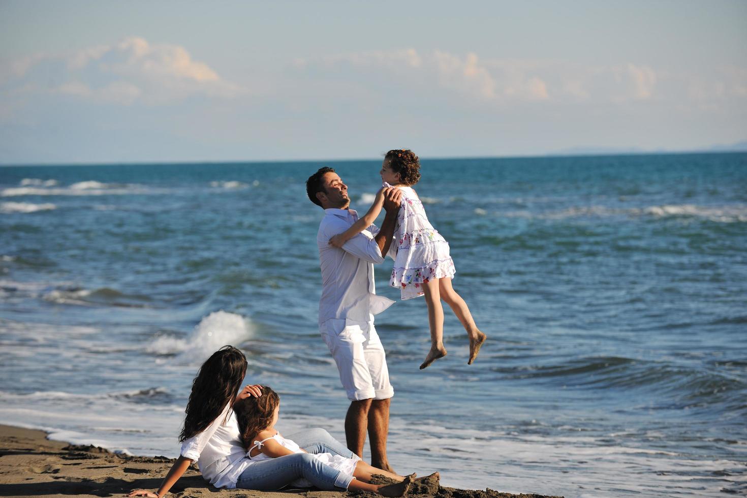 gelukkig jong familie hebben pret Aan strand foto