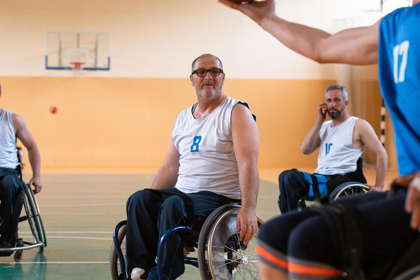 gehandicapten oorlog veteranen in rolstoelen met professioneel uitrusting Speel basketbal bij elkaar passen in de zaal.de concept van sport- met handicaps foto