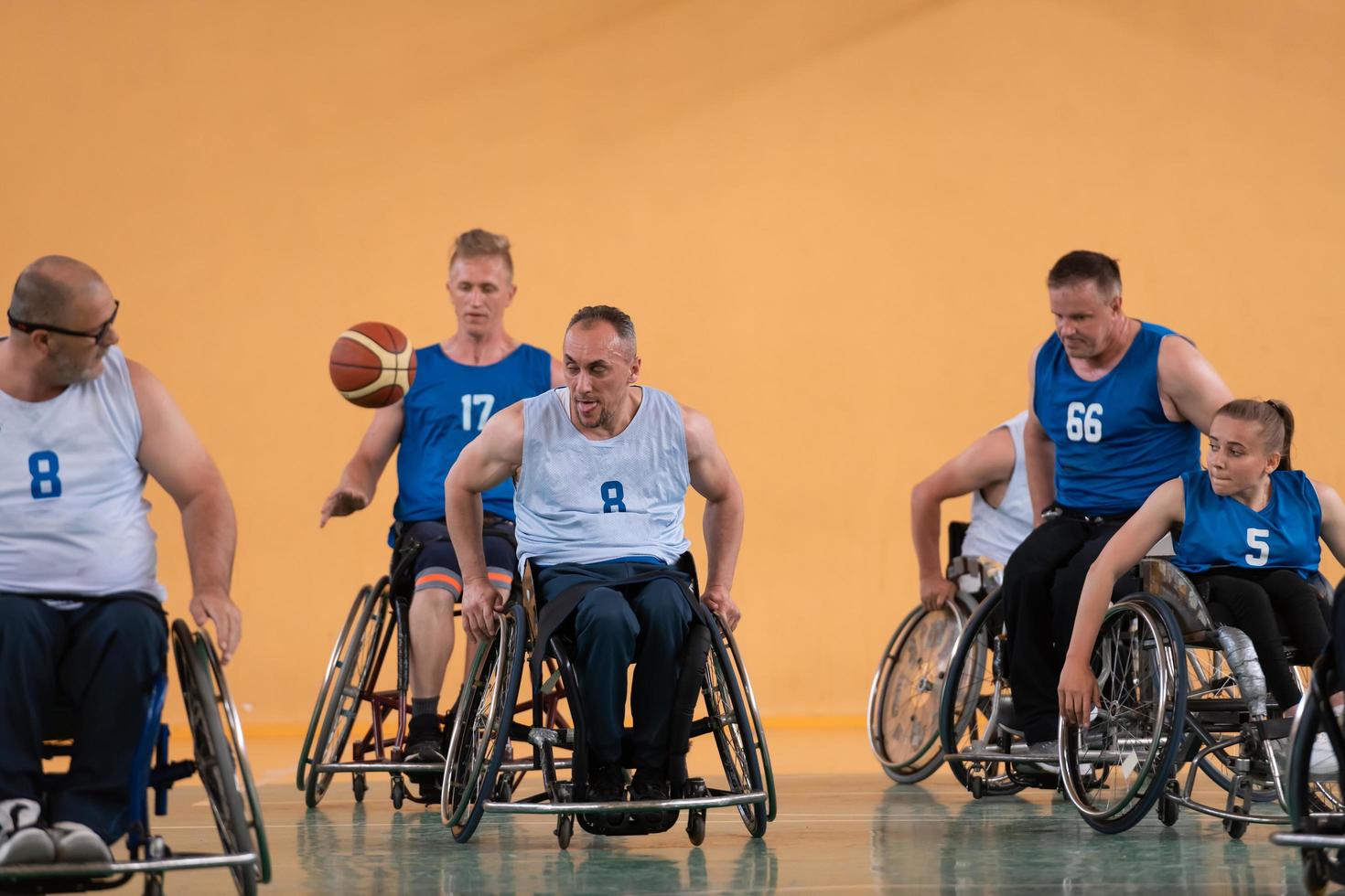 gehandicapt oorlog veteranen gemengd ras tegengesteld basketbal teams in rolstoelen gefotografeerd in actie terwijl spelen een belangrijk bij elkaar passen in een modern hal. foto