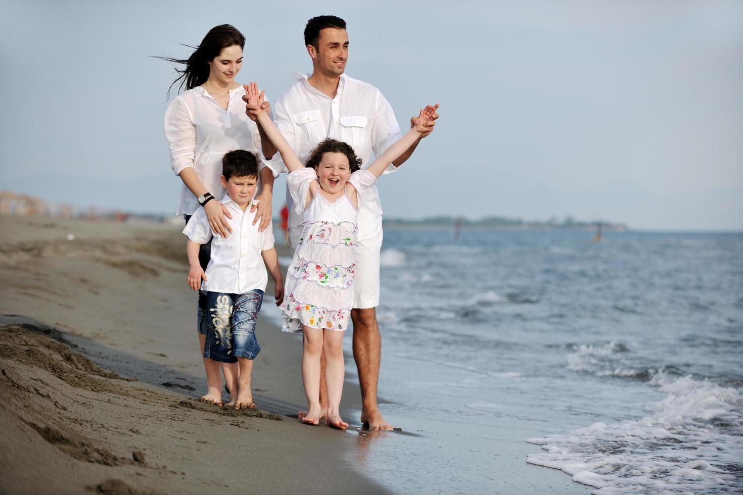 gelukkig jong familie hebben pret Aan strand foto